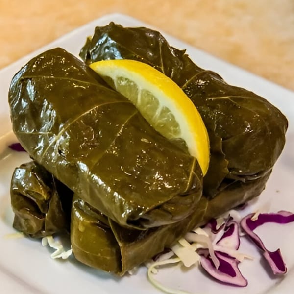 Shish Taouk Restaurant's dolmades, grape leaves stuffed with rice, served with a lemon wedge and shredded cabbage.